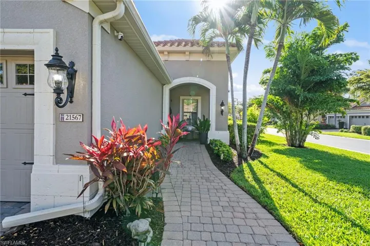 The property features a paver walkway leading to the entrance, a well-maintained lawn, and established palm trees