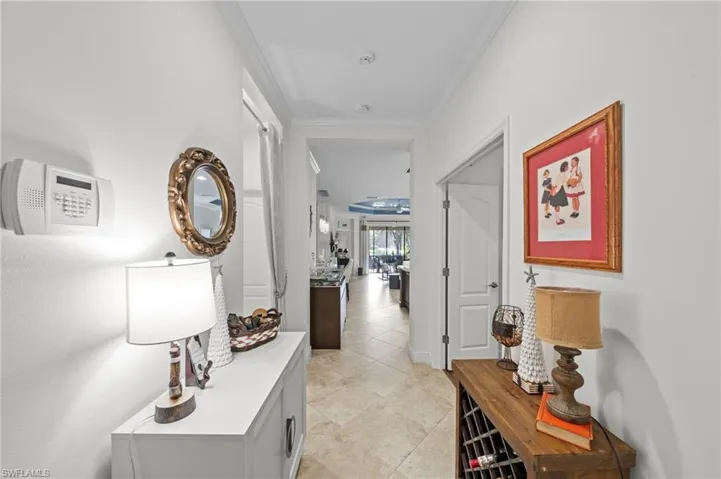 The property features a hallway with light-colored tile flooring and white walls, leading to an open living area