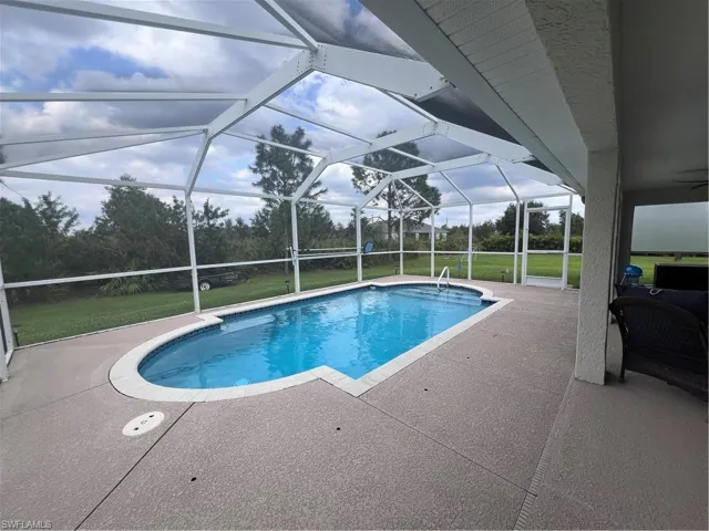 View of swimming pool featuring a lanai, a lawn, and a patio area