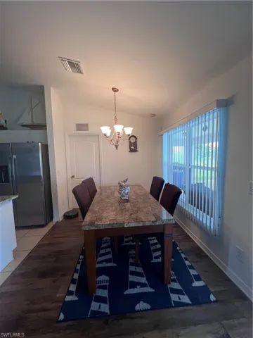 Dining space featuring tile patterned flooring, vaulted ceiling, and a notable chandelier