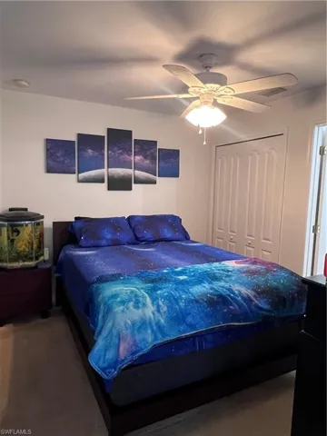 Carpeted bedroom with ceiling fan and a closet