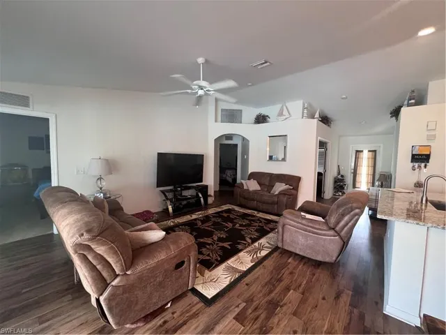 Living room with ceiling fan, lofted ceiling, dark hardwood / wood-style floors, and sink