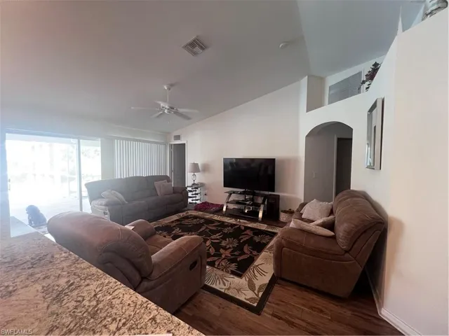 Living room featuring vaulted ceiling, dark hardwood / wood-style flooring, and ceiling fan