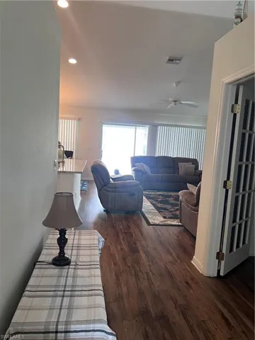Living room with dark hardwood / wood-style flooring and ceiling fan