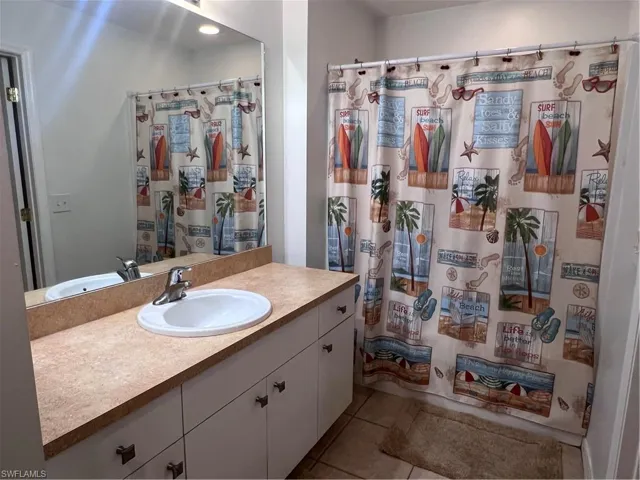 Bathroom with tile patterned flooring, a shower with shower curtain, and vanity