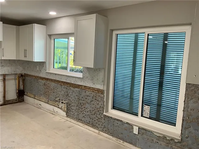 Kitchen with white cabinetry and large windows making it light and bright for cooking and dining.
