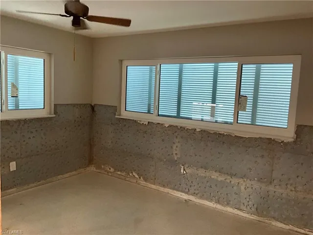 Second bedroom with a ceiling fan and large storm windows.