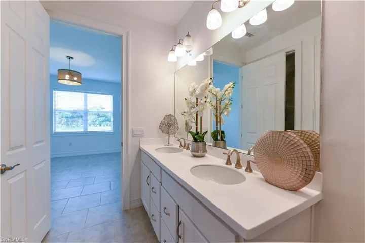 Bathroom with double vanity and light tile patterned floors