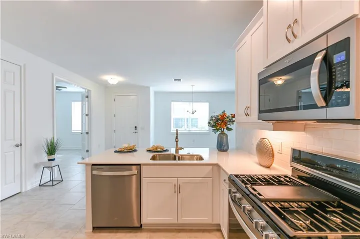 Kitchen with stainless steel appliances, white cabinets, a peninsula, and healthy amount of natural light