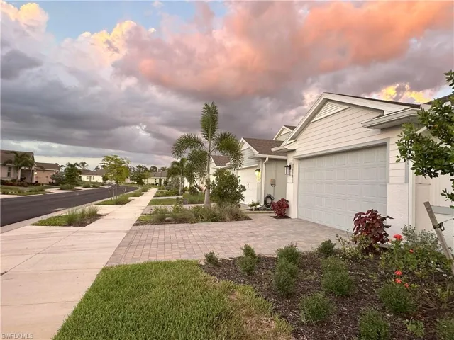 View of front of property featuring decorative driveway, a garage, and a residential view