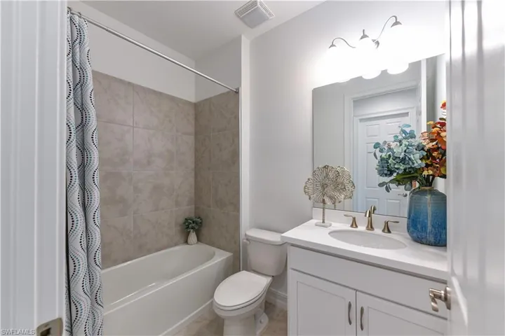 Bathroom featuring shower / bathtub combination with curtain and vanity
