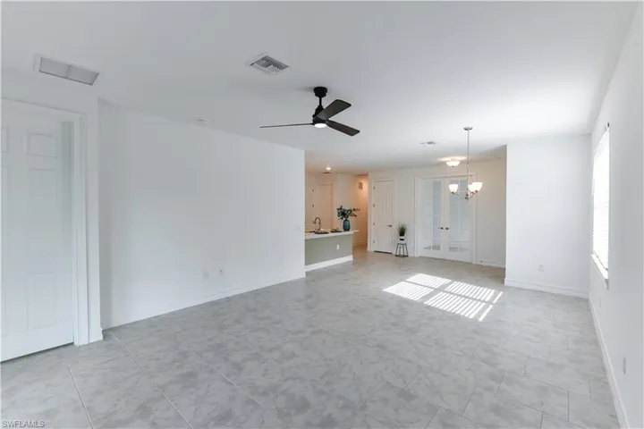 Unfurnished room featuring a ceiling fan, french doors, and a chandelier