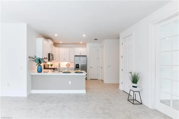 Kitchen with light countertops, white cabinets, a peninsula, stainless steel appliances, and recessed lighting