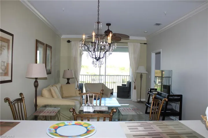 Living area with crown molding, suspended lighting, and carpet flooring