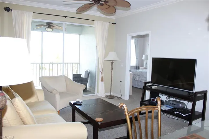 Living area featuring ceiling fan, ornamental molding, and carpet flooring