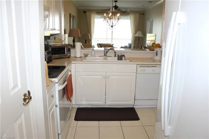 Kitchen with white appliances, white cabinets, light countertops, ceiling fan, and light tile patterned floors