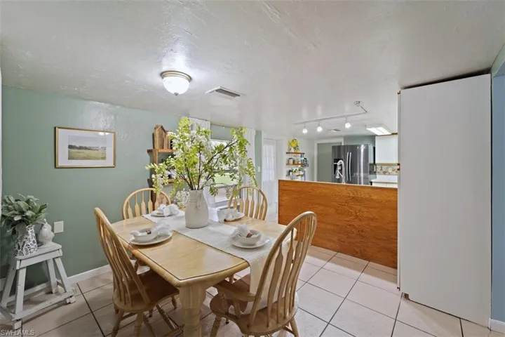 Tiled dining room featuring a textured ceiling and rail lighting