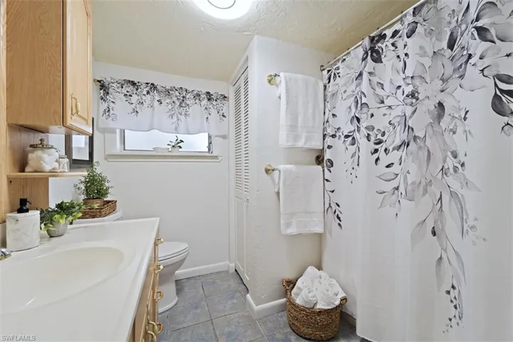 Bathroom featuring tile patterned floors, a shower with curtain, vanity, a textured ceiling, and toilet