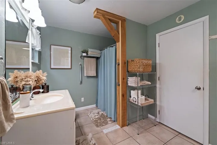Bathroom with tile patterned flooring, curtained shower, and vanity