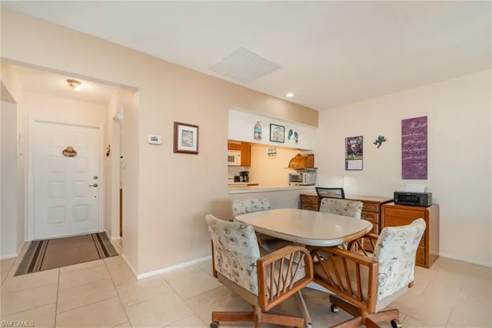 Tiled entry foyer with a paneled door, flush-mount lighting, and a kitchen pass-through