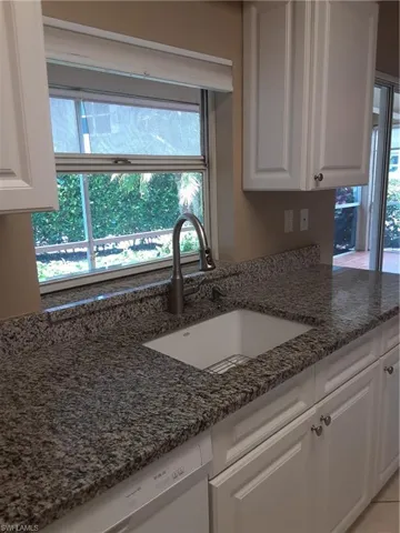 Kitchen featuring sink, dark stone countertops, and white cabinets