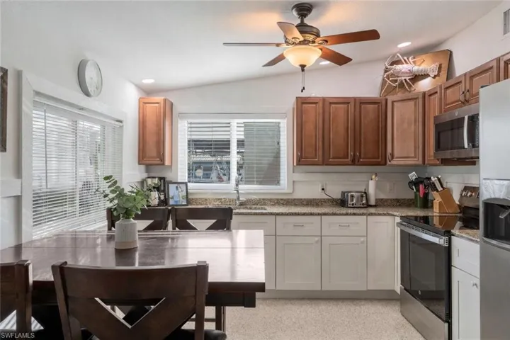 Kitchen with stainless steel appliances, recessed lighting, ceiling fan, lofted ceiling, and light stone countertops