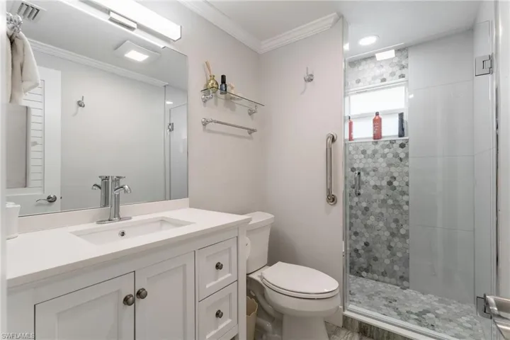 Full bath featuring a stall shower, vanity, and ornamental molding
