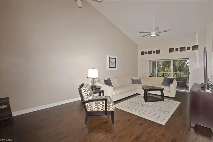 Living room featuring high vaulted ceiling, ceiling fan, vinyl tile flooring