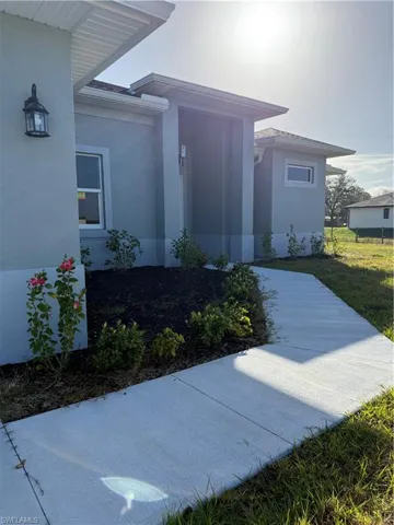 Doorway to property with stucco siding and lawn