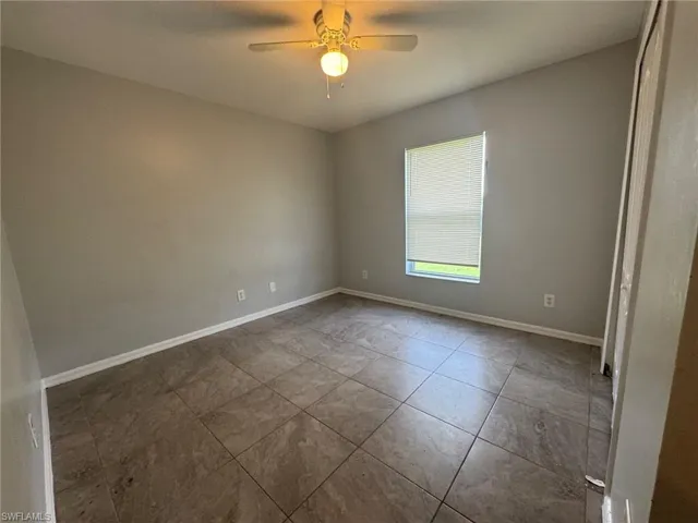 Empty room featuring a ceiling fan and baseboards