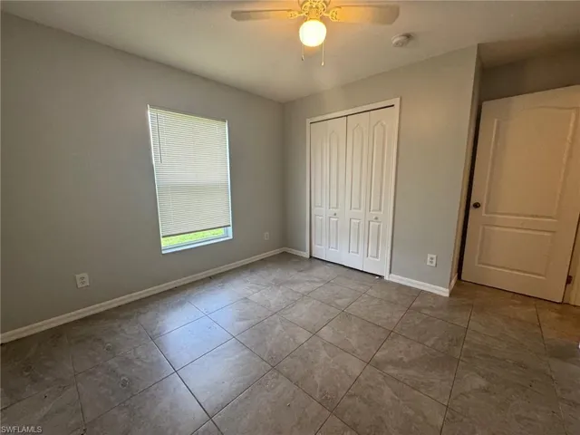 Unfurnished bedroom with ceiling fan, a closet, and tile patterned floors