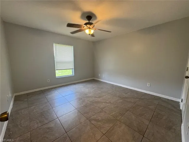 Unfurnished room with ceiling fan, dark tile patterned floors, and a textured ceiling