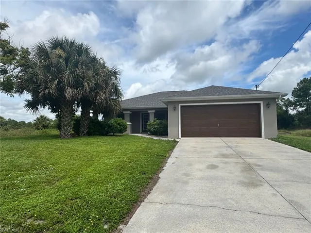 View of front of property featuring stucco siding, a front lawn, an attached garage, concrete driveway, and roof with shingles