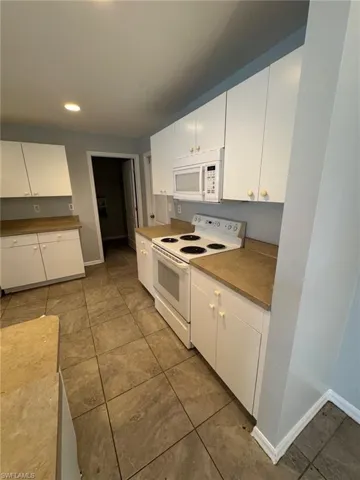 Kitchen with white cabinetry, white appliances, recessed lighting, and light tile patterned floors