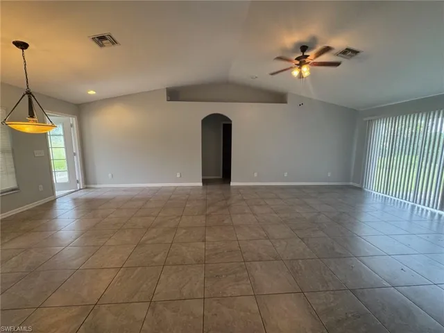 Tiled empty room featuring ceiling fan and arched walkways