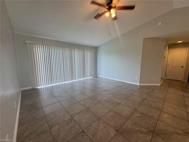 Tiled spare room with vaulted ceiling and ceiling fan