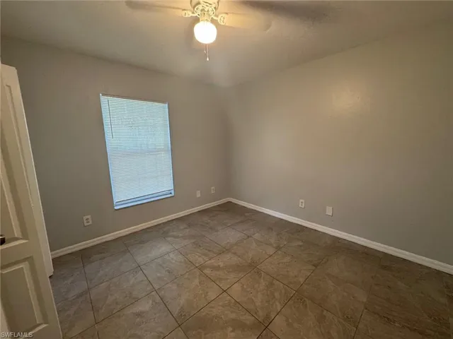 Empty room featuring a ceiling fan and baseboards