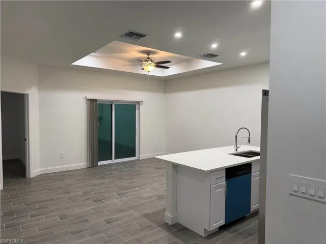 Kitchen featuring a tray ceiling, dishwasher, wood tiled floors, white cabinets, and recessed lighting