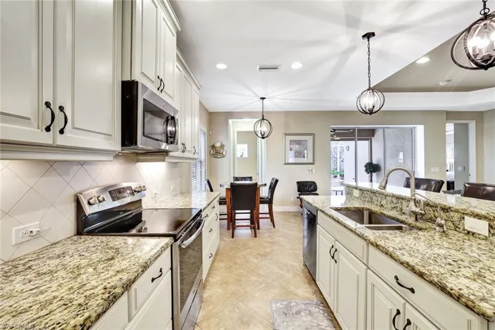 Kitchen with tasteful backsplash, visible vents, hanging light fixtures, appliances with stainless steel finishes, and a sink