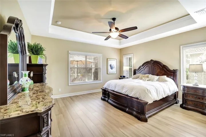 Bedroom featuring a tray ceiling, light wood-type flooring, and visible vents
