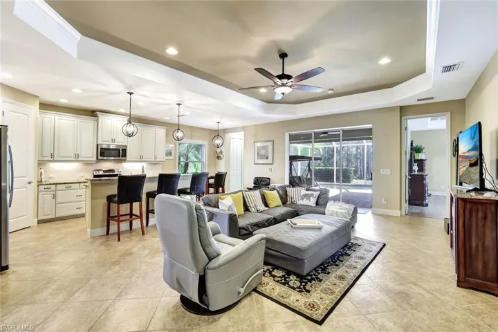 Living area featuring recessed lighting, a raised ceiling, visible vents, and ceiling fan