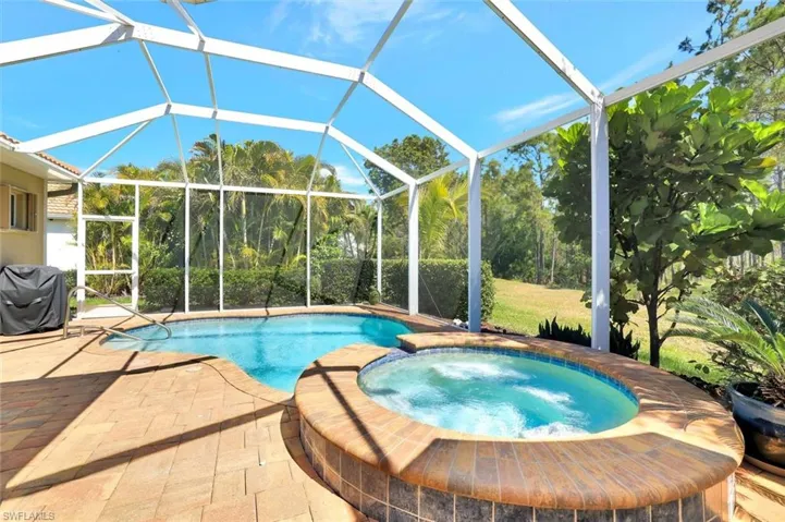View of swimming pool with a patio area, a pool with connected hot tub, and glass enclosure