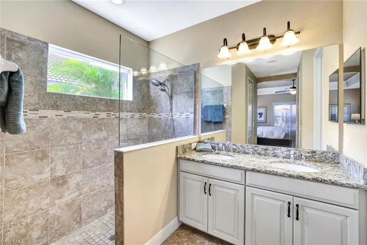 Bathroom featuring a walk in shower, a sink, and ensuite bathroom