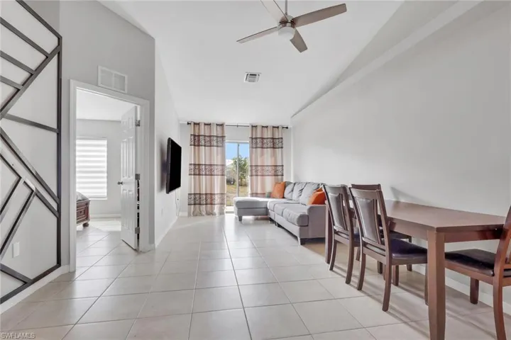 Living area featuring ceiling fan, light tile patterned floors, and lofted ceiling