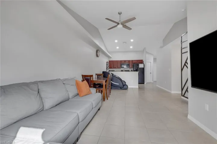 Living room with ceiling fan, light tile patterned floors, vaulted ceiling, and recessed lighting
