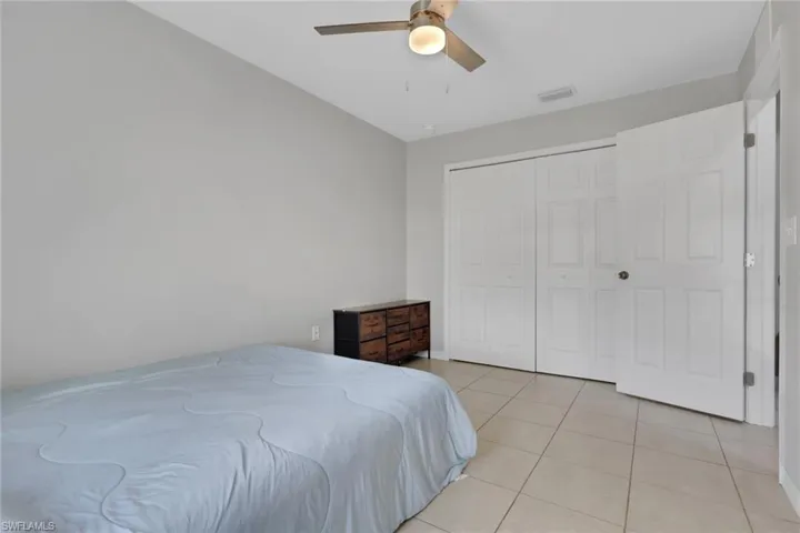 Bedroom with light tile patterned floors, ceiling fan, and a closet