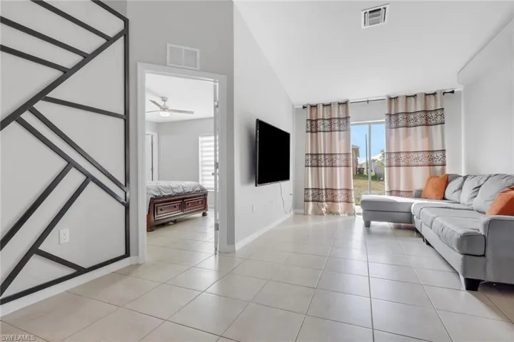 Living area featuring vaulted ceiling, light tile patterned floors, and a ceiling fan