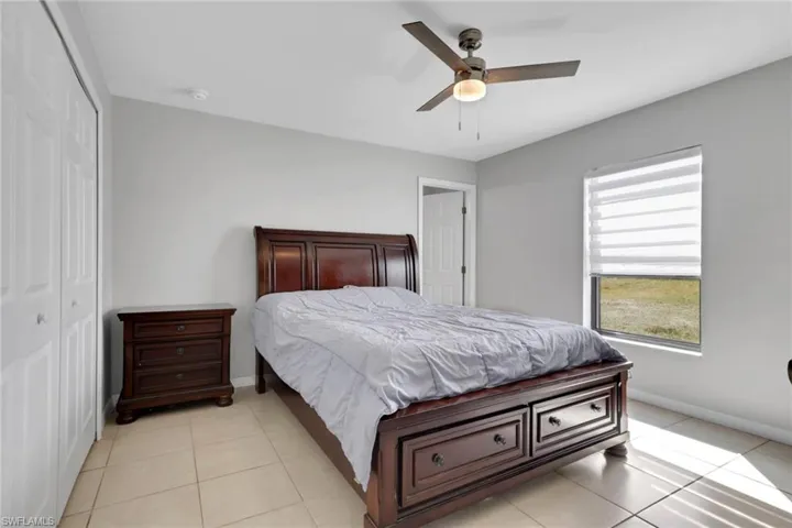 Bedroom with a closet, ceiling fan, and light tile patterned flooring