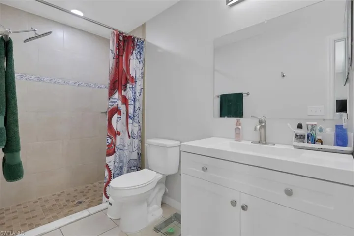 Bathroom featuring vanity, light tile patterned floors, and a shower stall