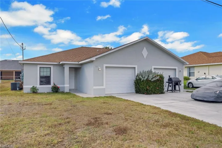 Single story home featuring stucco siding, a front lawn, a garage, roof with shingles, and driveway